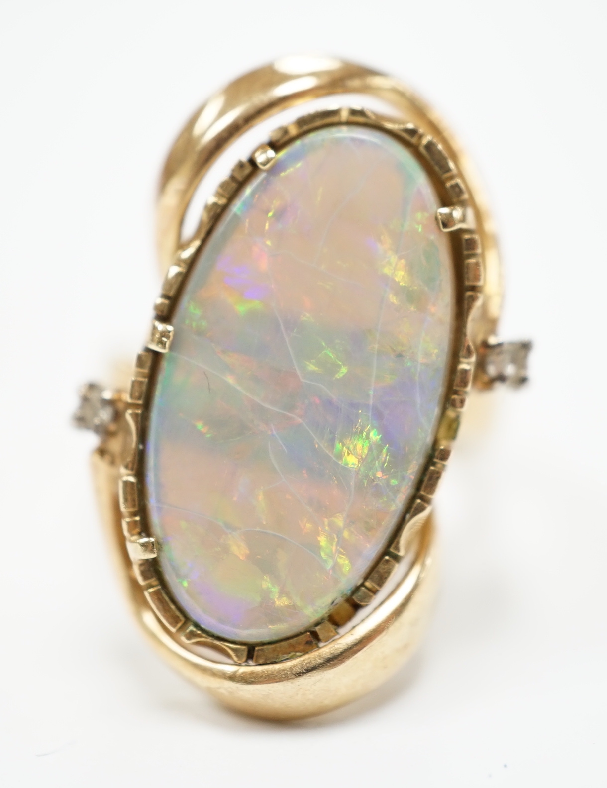 A yellow metal and oval cut black opal set dress ring, with two stone diamond chip set border, size M, gross weight 8.2 grams.